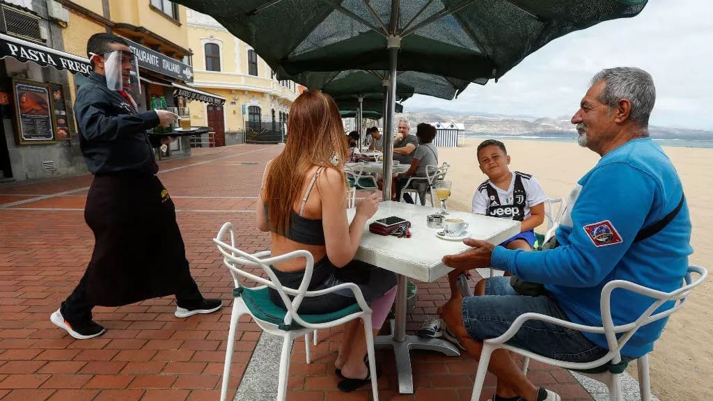 Un mesero atiende a varios clientes en el paseo marítimo de la playa de Las Canteras durante la reapertura en algunas provincias españolas durante la fase 1, en medio del brote de la enfermedad del coronavirus Covid-19 en la isla de Gran Canaria, España, el 11 de mayo de 2020. © Borja Suárez / Reuters