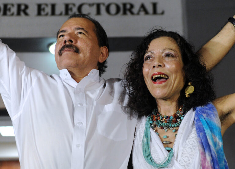 Daniel Ortega y Rosario Murillo alzando sus brazos en señal de celebración.