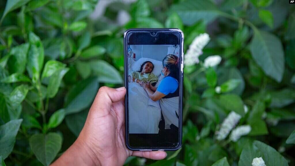 Maynor Cardona muestra una foto en su teléfono celular de su hija, Yenifer Yulisa Cardona Tomás, en el hospital en Texas, mientras recibe una visita.