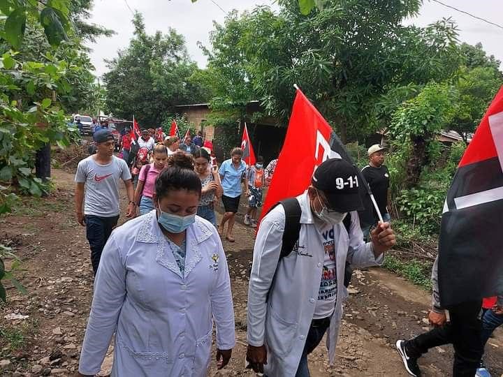 Trabajador de la salud sostiene bandera del FSLN en caminata partidaria en Puerto Morazán Chinandega. Crédito Cortesía.