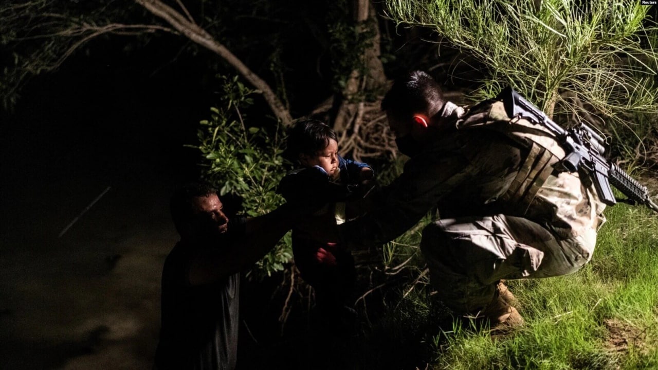 Un traficante de personas pasa a un niño migrante que busca asilo a un miembro de la Guardia Nacional de los EEUU después de cruzar el río Grande hacia los Estados Unidos desde México en Roma, EEUU, el 10 de junio de 2021.