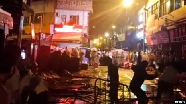 Los manifestantes que protestan por las restricciones de la enfermedad por coronavirus (COVID-19) arrojan botellas de vidrio a la policía antidisturbios en Guangzhou, provincia de Guangdong, China en esta captura de pantalla tomada de un video de las redes sociales publicado el 30 de noviembre de 2022