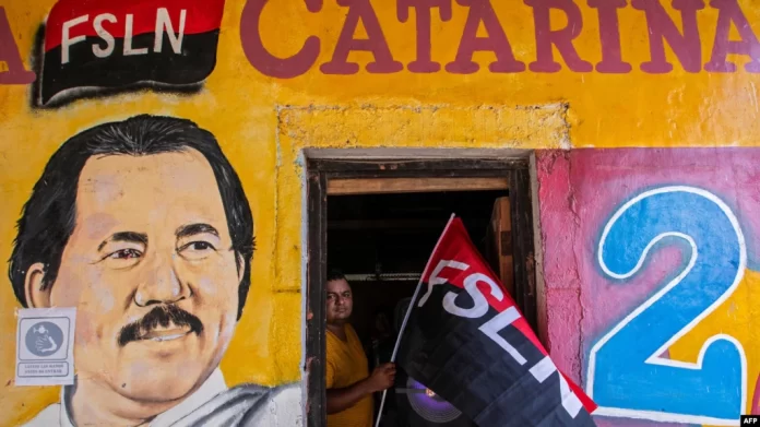 (ARCHIVOS) En esta foto de archivo tomada el 17 de julio de 2020, un hombre sostiene una bandera del Frente Sandinista de Liberación Nacional (FSLN) junto a un mural que representa al presidente de Nicaragua, Daniel Ortega. Foto por INTI OCON / AFP) iglesia católica