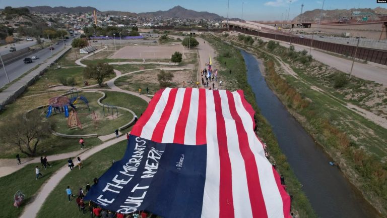 Migrantes venezolanos portan una inmensa bandera de EEUU en una protesta contra la nueva política de inmigración de Estados Unidos cerca del Río Bravo en Cuidad Juárez, México, el 31 de octubre de 2022.
