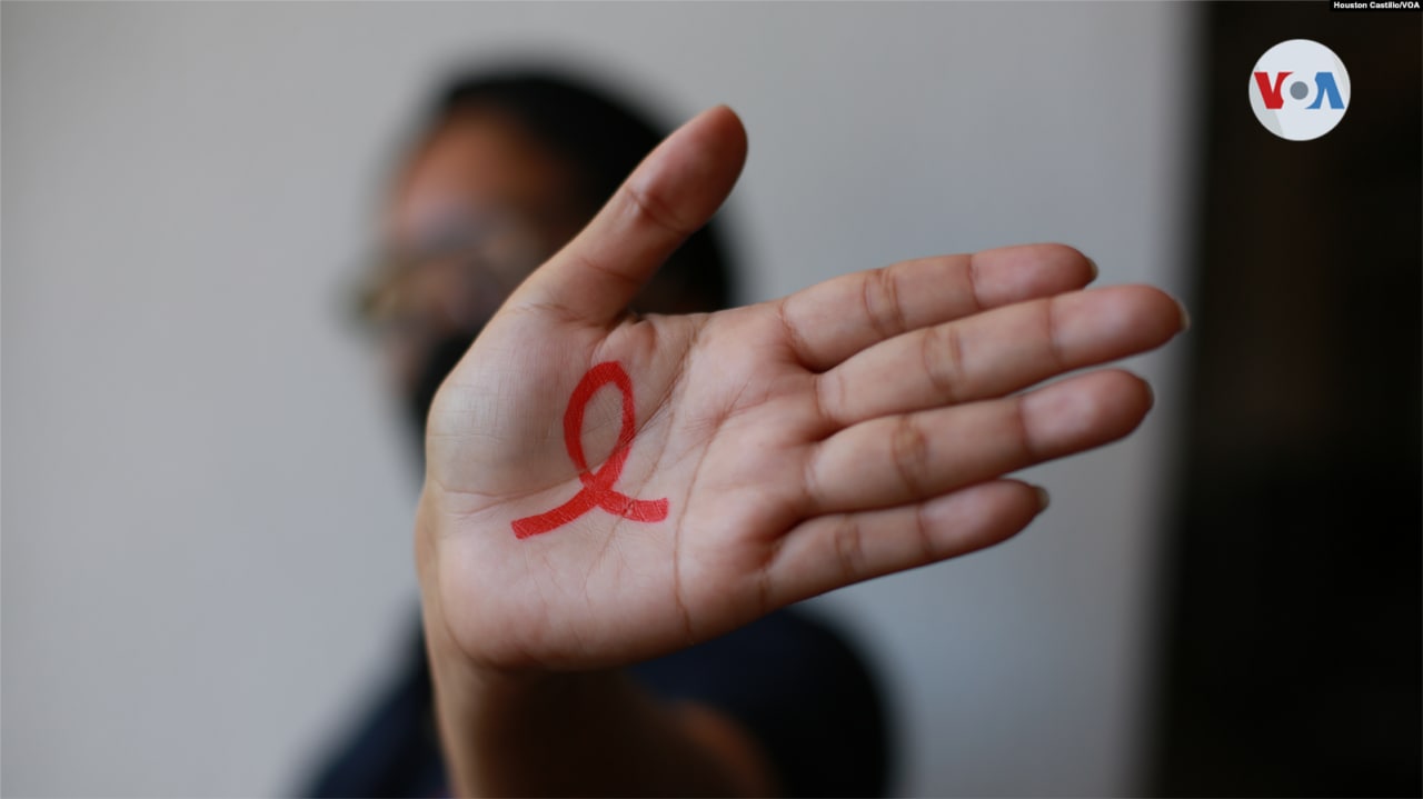 Una persona portadora de VIH muestra un lazo rojo en su mano, un símbolo internacional ideado para mostrar apoyo a la lucha contra el SIDA y solidaridad con las víctimas de la enfermedad.