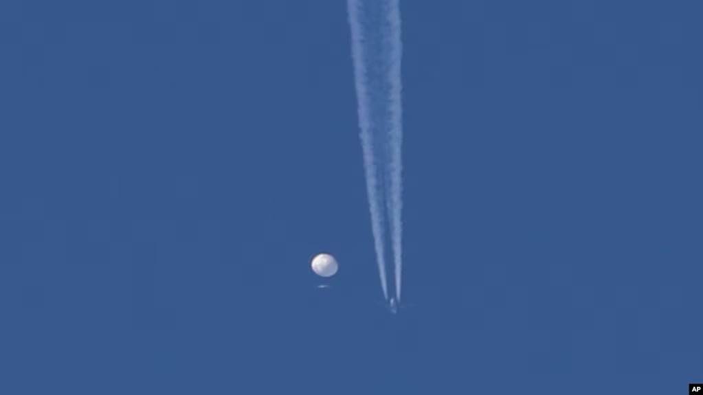 Un gran globo se desplaza sobre el área de Kingston, N.C., con un avión y su estela debajo de él. Estados Unidos dice que es un globo espía chino que se mueve hacia el este sobre EEUU a una altitud de 18.600 metros. (Brian Branch via AP)