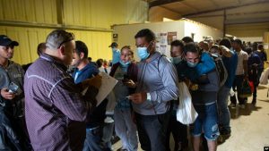 ARCHIVO - Varias personas hacen fila para abordar un autobús que los llevará al aeropuerto de San Antonio en un almacén manejado por el grupo sin fines de lucro Mission: Border Hope, operado por la Iglesia Metodista Unida, en mayo de 2022, en Eagle Pass, EEUU.