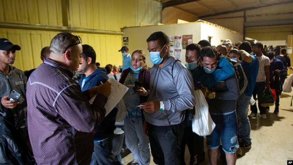 ARCHIVO - Varias personas hacen fila para abordar un autobús que los llevará al aeropuerto de San Antonio en un almacén manejado por el grupo sin fines de lucro Mission: Border Hope, operado por la Iglesia Metodista Unida, en mayo de 2022, en Eagle Pass, EEUU.