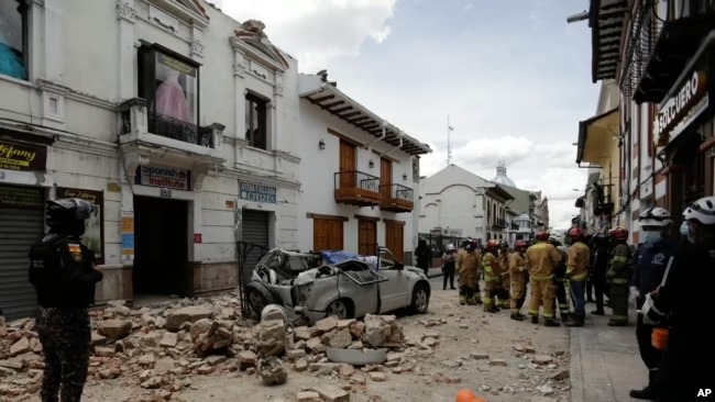 Equipos de rescate junto a un automóvil aplastado por los escombros después de un terremoto en Cuenca, Ecuador, el sábado 18 de marzo de 2023. (Foto AP/Xavier Caivinagua)