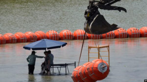 Trabajadores toman un descanso de colocar boyas para que sean utilizadas como barrera fronteriza en el río Bravo, el miércoles 12 de julio de 2023, a la altura de Eagle Pass, Texas. (AP Foto/Eric Gay)