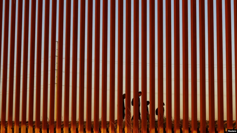 Migrantes que intentan llegar a Estados Unidos caminan junto a un muro fronterizo en Ciudad Juárez, México, visto desde El Paso, EEUU, el 8 de mayo de 2023.