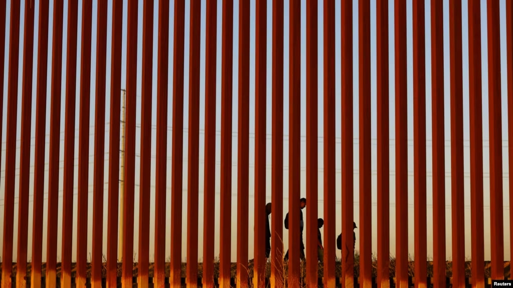 Migrantes que intentan llegar a Estados Unidos caminan junto a un muro fronterizo en Ciudad Juárez, México, visto desde El Paso, EEUU, el 8 de mayo de 2023.