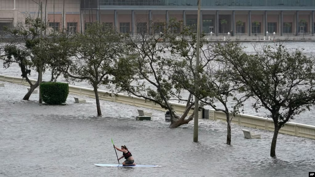 Una persona monta su tabla de remo en medio de la inundada Bayshore Blvd en el centro de Tampa, Florida, el miércoles 30 de agosto de 2023.