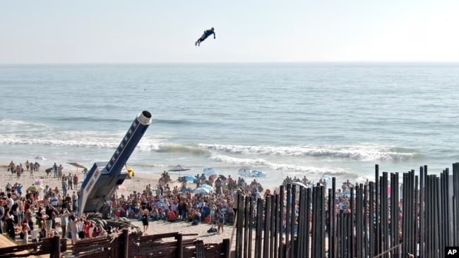 ARCHIVO - David “The Human Cannonball” Smith Jr. sobrevuela la valla fronteriza entre Estados Unidos y México desde el área de Playas de Tijuana en Tijuana hasta San Diego, durante un festival de arte el 27 de agosto de 2005.
