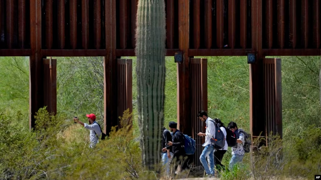 Migrantes atraviesan compuertas del muro fronterizo entre EEUU y México en el sector de Tucson, Arizona, el 29 de agosto de 2023.