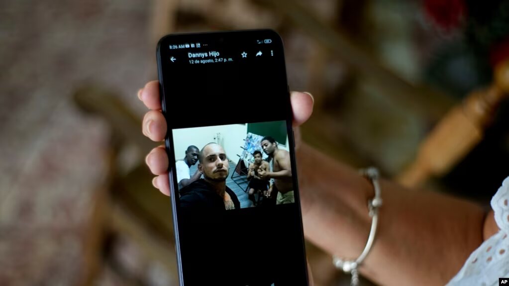 Marilin Vinent sostiene una fotografía de su hijo Dannys Castillo con otros cubanos en Rusia, enviada en un mensaje de su hijo durante una entrevista en su casa en La Habana, Cuba, el viernes 8 de septiembre de 2023.