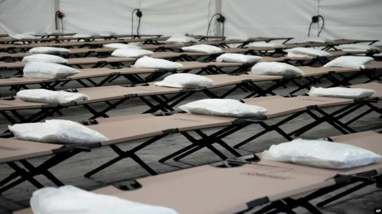 Bolsas con una almohada, toalla y sábanas están colocadas en catres al interior de una carpa dormitorio durante una gira de prensa a un albergue que la ciudad de Nueva York está montando para albergar hasta 1.000 migrantes en el barrio de Queens, el 5 de agosto de 2023.