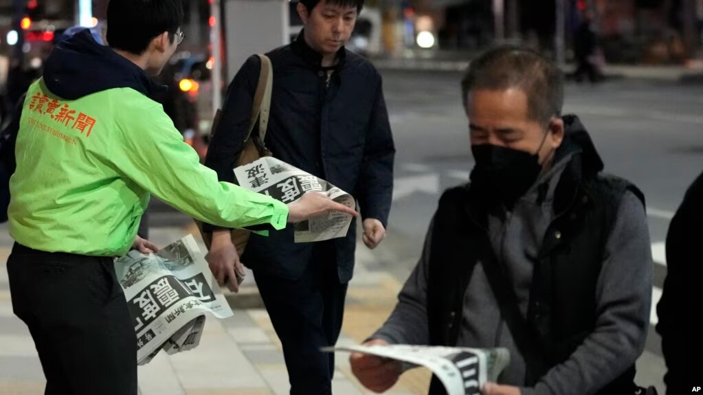 Personas en Tokio leen la edición extraordinaria de un diario reportando los sismos del 1 de enero en Japón.