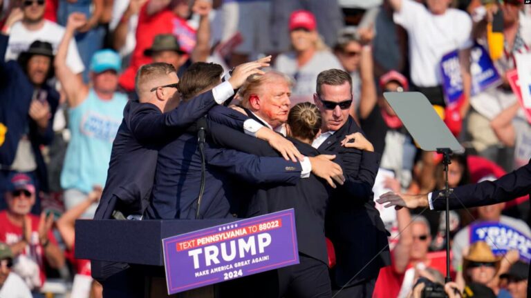 El candidato presidencial republicano y expresidente Donald Trump recibe ayuda para salir del escenario en un evento de campaña en Butler, Pensilvania, el 13 de julio de 2024.